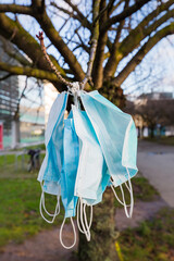 used covid masks hanging from a tree