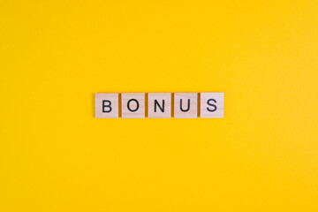 Word Bonus formed by wooden letters on orange background. Top view. Copy space
