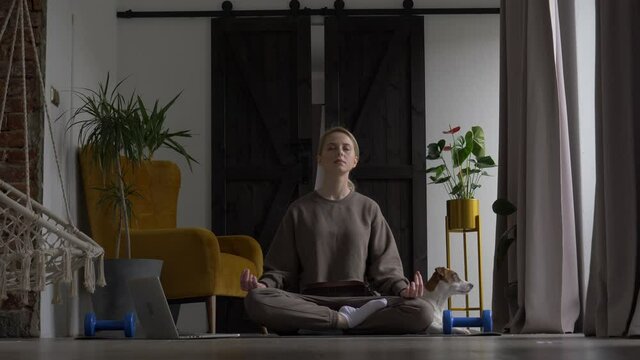 girl doing meditation on the rug at home next to the dog