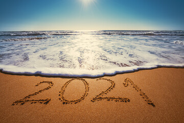 Happy New Year 2021 concept, lettering on the beach. Written text on the sea beach at sunrise.