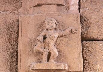 Hampi, Karnataka, India - November 5, 2013: Sri Krishna temple in ruins. Red stone fresco of the god depicted as a young kid, set in wall.