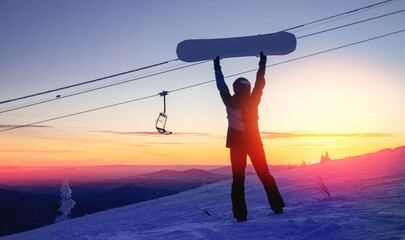 Silhouette of snowboarder against setting sun in lift ski resort