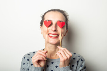 Young woman closed her eyes with hearts on sticks on a light background. Valentine's day, birthday. Banner