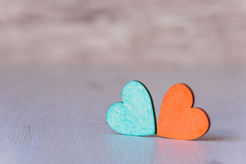 Background with two green and orange hearts, on wooden background
