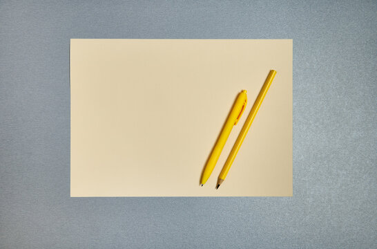 Yellow Office Tools On A Gray Background. Pen, Pencil And Sheet Of Paper. Flat Lay, Copy Space, Top View