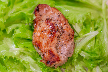 Appetizing juicy piece of well-done meat and fresh green lettuce leaves