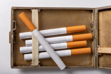 Cigarettes in a metal cigarette case. Stimulants for adults dangerous to health.