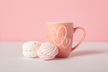 Mug with earring and sweets on a pink background. Valentine's Day concept. Banner