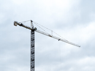 silhouette of a construction crane against a cloudy sky on a high rise building site