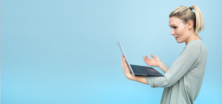 Genervte junge blonde Frau h&auml;lt Laptop in der Hand