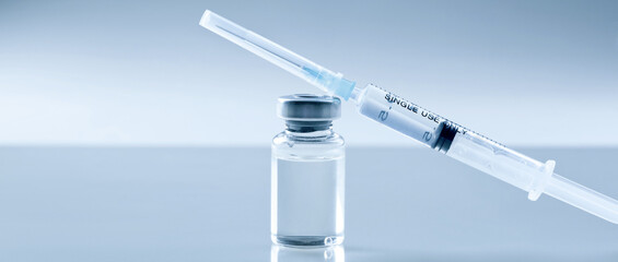 Medical syringe with a needle and a bollte with vaccine.