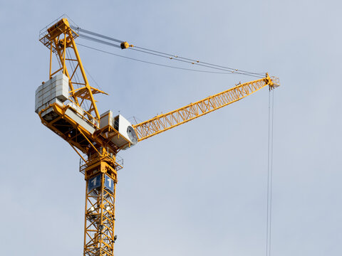 a yellow luffing jib construction crane on a high rise building site
