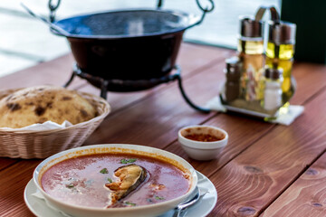 A fish soup and bread at the table in the restaurant on the river.