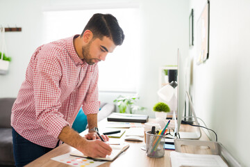 Latin man in his 20s is planning his work week at the office