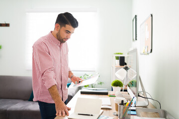 Obraz premium Hispanic guy is reviewing some work papers at his desk