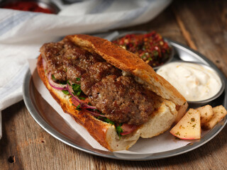 meatball sandwich with mezes on a metal plate on wooden background
