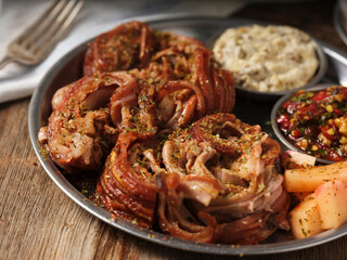 kokorec with mezes with a fork on a metal plate on wooden background
