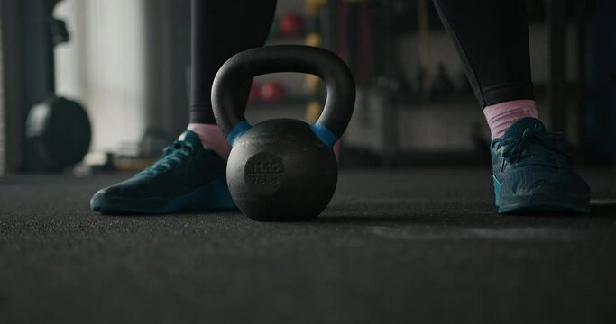 Sportswoman exercising with kettlebell in gym.