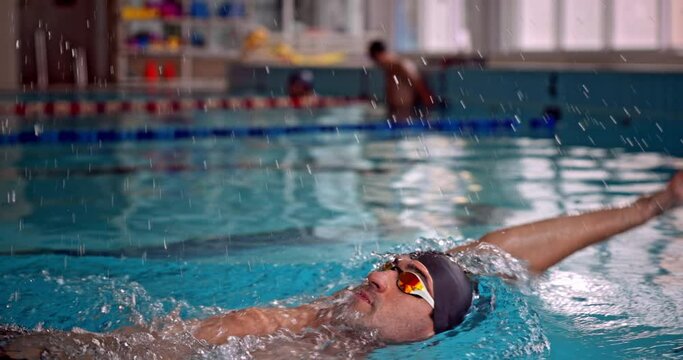 Professional amputee athlete swimming backstroke in indoor pool