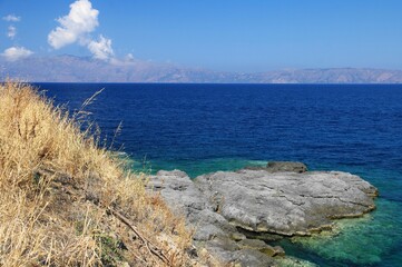 Krajobraz z suchą trawą, skałą, morzem, niebem i chmurami, Kreta, Grecja / Landscape with dry...