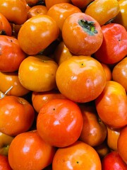 Close-up photo of Persimmons in market. Group of fruits background.