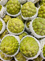 Close-up photo of Sugar Apple in market. Group of fruits background. Sweetsop or Custard Apple.