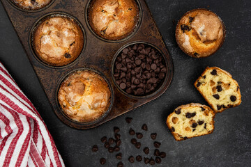 Chocolate chip muffins in a muffin tin and on the counter