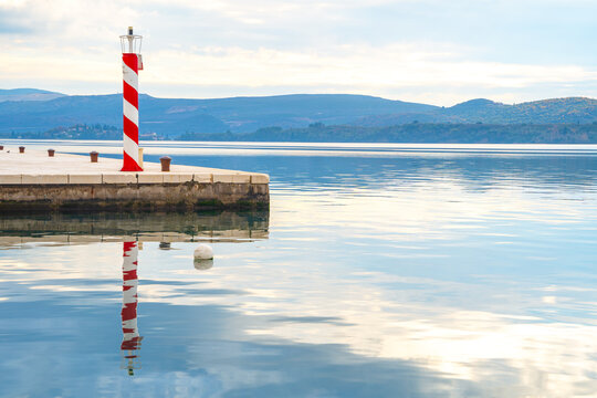 Lighthouse on coast to serve as navigational aid at sea, mark dangerous coastlines, hazardous shoals, reefs, rocks and safe entries to harbors. Calm mirror surface of water