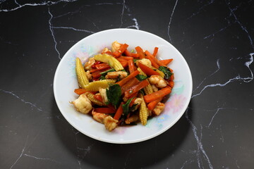 Hot and spicy stirred mixed vegetable with fresh peeled shrimp and seasoning with pepper and basil serving on the plate.