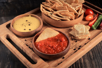 chips with sauce and vegetables on a dark wooden table