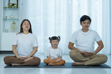 Happy parents with small preschooler girl meditation for positive emotions at home. Funny action.