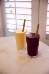 Two mango banana and mix berries healthy smoothies on marble table.