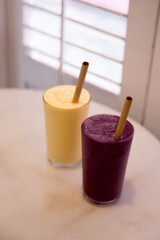 Two mango banana and mix berries healthy smoothies on marble table.