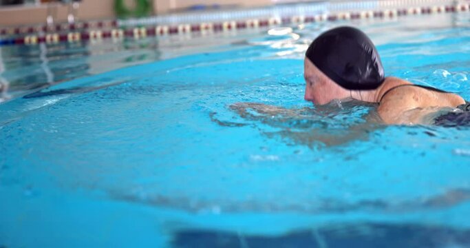 Older woman swimming in indoor pool