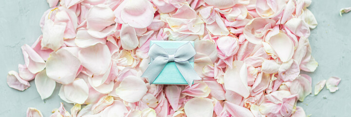 Obraz na płótnie Canvas Gift box lying on Rose petals pink color closeup, holiday background.