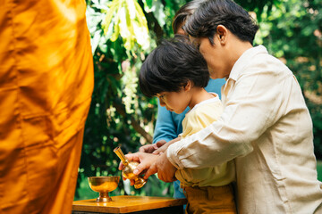 Family pouring water from golden grail after gave alms offering to monk.