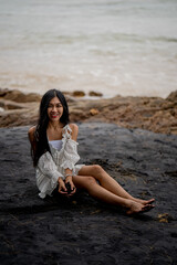 beautiful woman sitting on the black beach