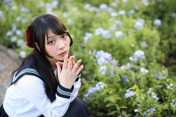 Fototapeta premium Asian school girl sitting with flower garden background