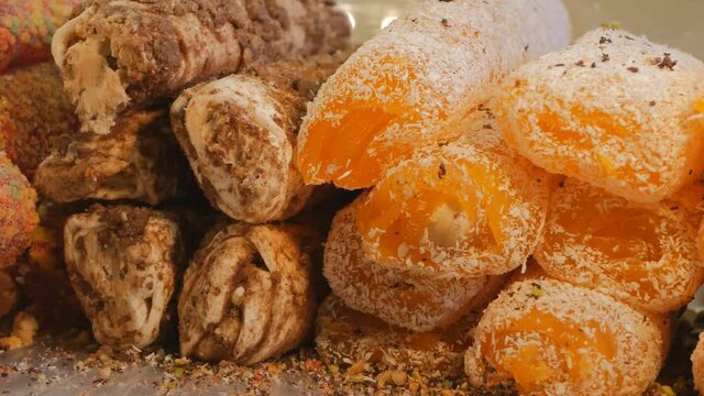 Turkish delight of various flavors is sprinkled with chocolate and coconut flakes. Dolly shooting Turkish delight. 4K close-up