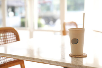 Iced coffee with paper glass in coffee shop background