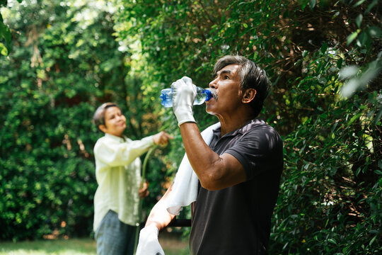 Senior Elderly Man Take A Break Drinking Water After Working At Garden.