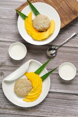 Top view of Thai dessert, Mango Sticky rice with coconut milk on wooden background, copy space juicy mango dessert