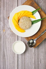 Top view of Thai dessert, Mango Sticky rice with coconut milk on wooden background, copy space juicy mango dessert