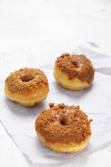 Obraz na płótnie Canvas Donat or Donut or Doughnut as circle with hole sweet bread topped with caramel and biscuit crumbs. Pile of doughnut in white shiny background