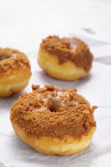 Obraz na płótnie Canvas Donat or Donut or Doughnut as circle with hole sweet bread topped with caramel and biscuit crumbs. Pile of doughnut in white shiny background