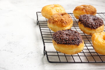 Top view of Donat or Donut or Doughnut as circle with hole sweet bread topped with caramel and biscuit crumbs, chocolate glazed with chocolate sprinkles. Selective focus, copy space,white  background
