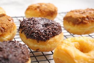Top view of Donat or Donut or Doughnut as circle with hole sweet bread topped with caramel and biscuit crumbs, chocolate glazed with chocolate sprinkles. Selective focus, copy space,white  background
