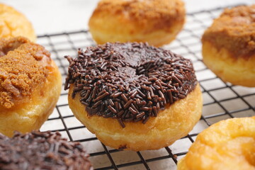 Top view of Donat or Donut or Doughnut as circle with hole sweet bread topped with caramel and biscuit crumbs, chocolate glazed with chocolate sprinkles. Selective focus, copy space,white  background
