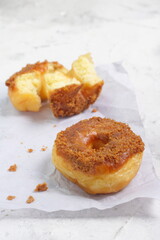 Donat or Donut or Doughnut as circle with hole sweet bread topped with caramel and biscuit crumbs. Selective focus, white shiny background