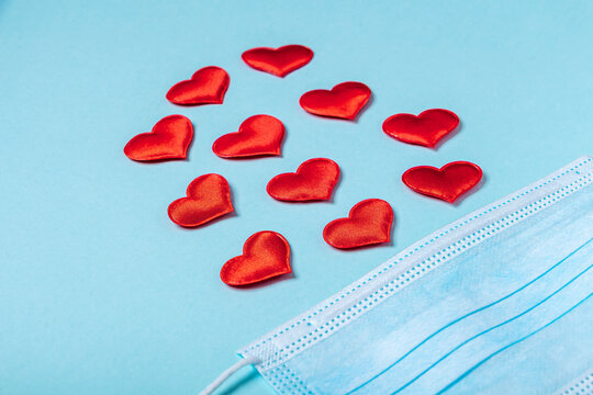 Valentine's day composition. Medical face protective mask and a lot of red hearts on blue background. New normal and coronavirus,  COVID-19 concept. Flat laym